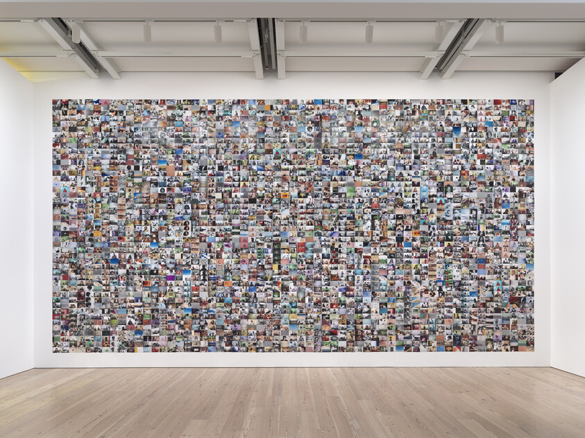 Large wall covered with hundreds of small, colorful photographs in a gallery setting.