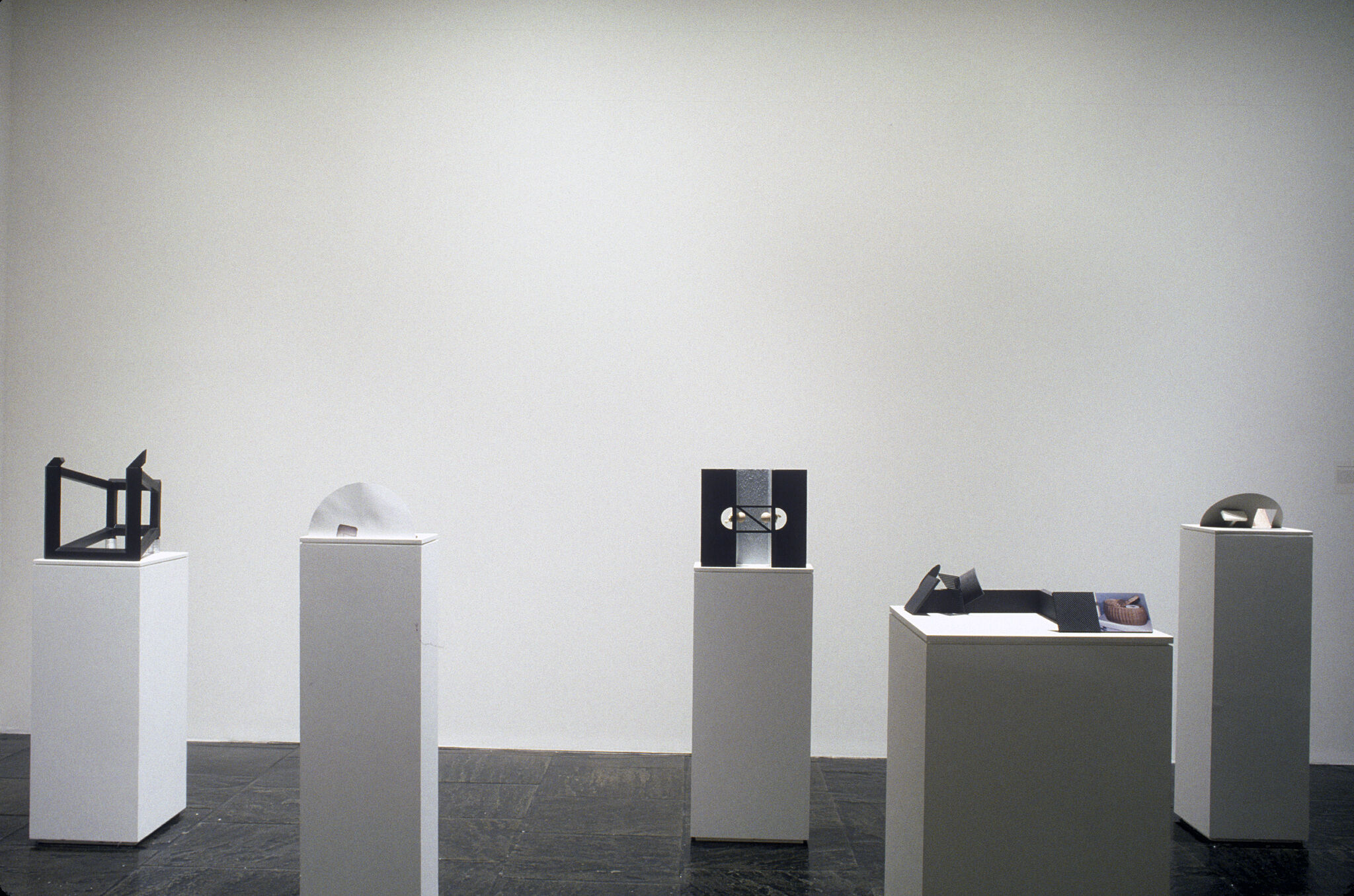 A gallery filled with white podiums displaying various sculptures by Vincent Fecteau.