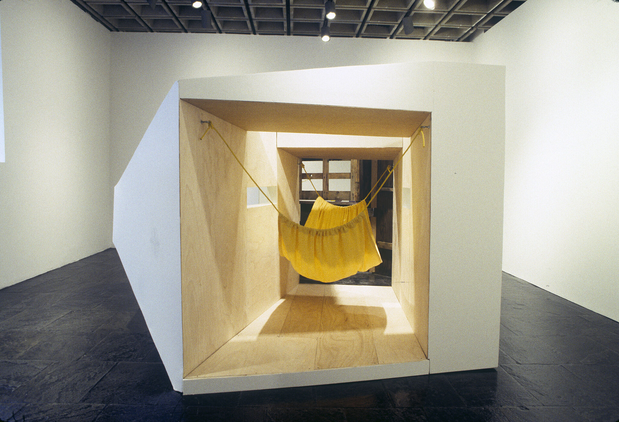 A large white and wooden sculpture with a yellow hammock inside.