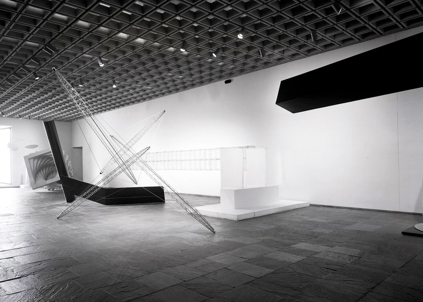 Black-and-white photograph of works of art in a gallery.