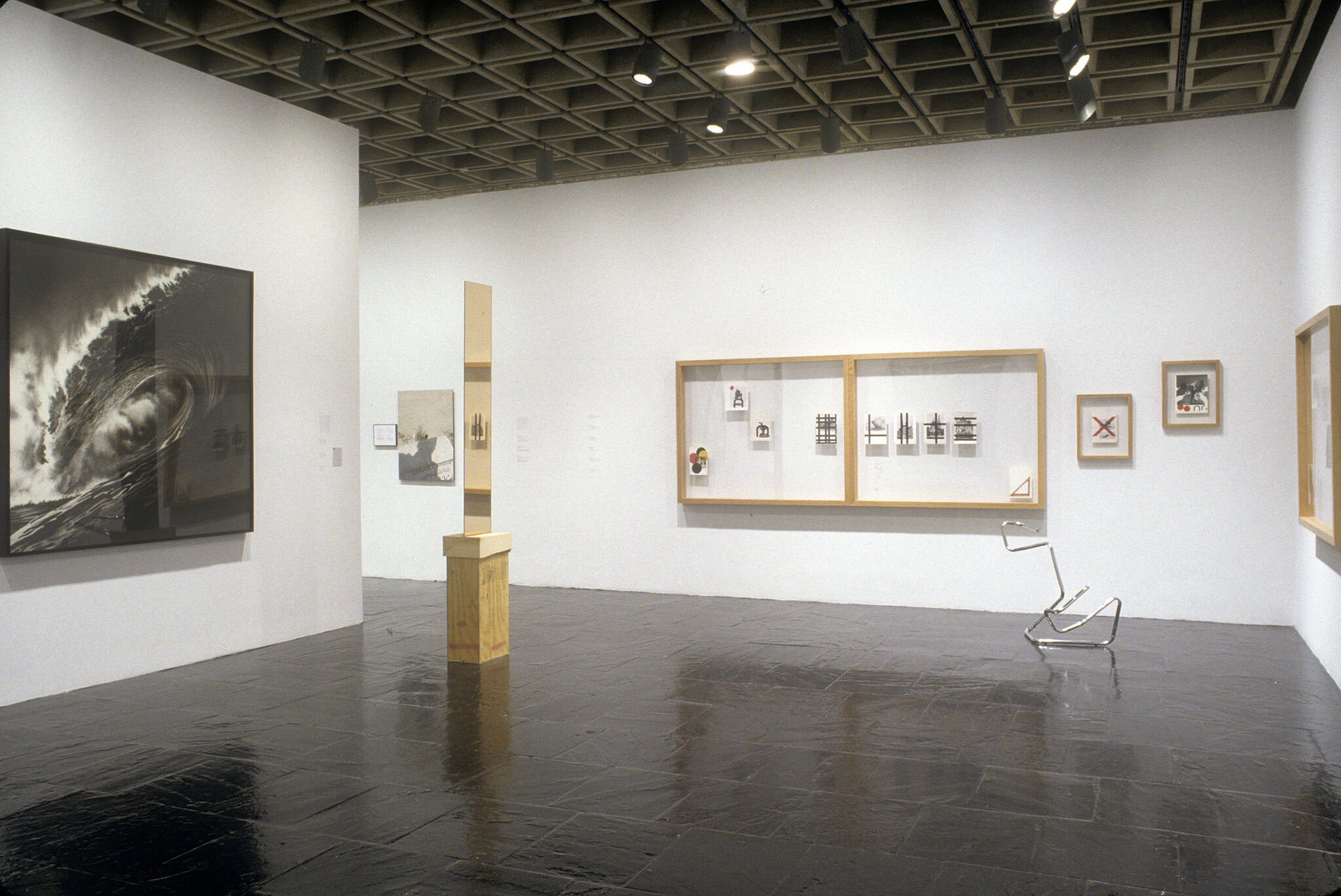 A gallery filled with prints and a sculpture made out of a metal tube.