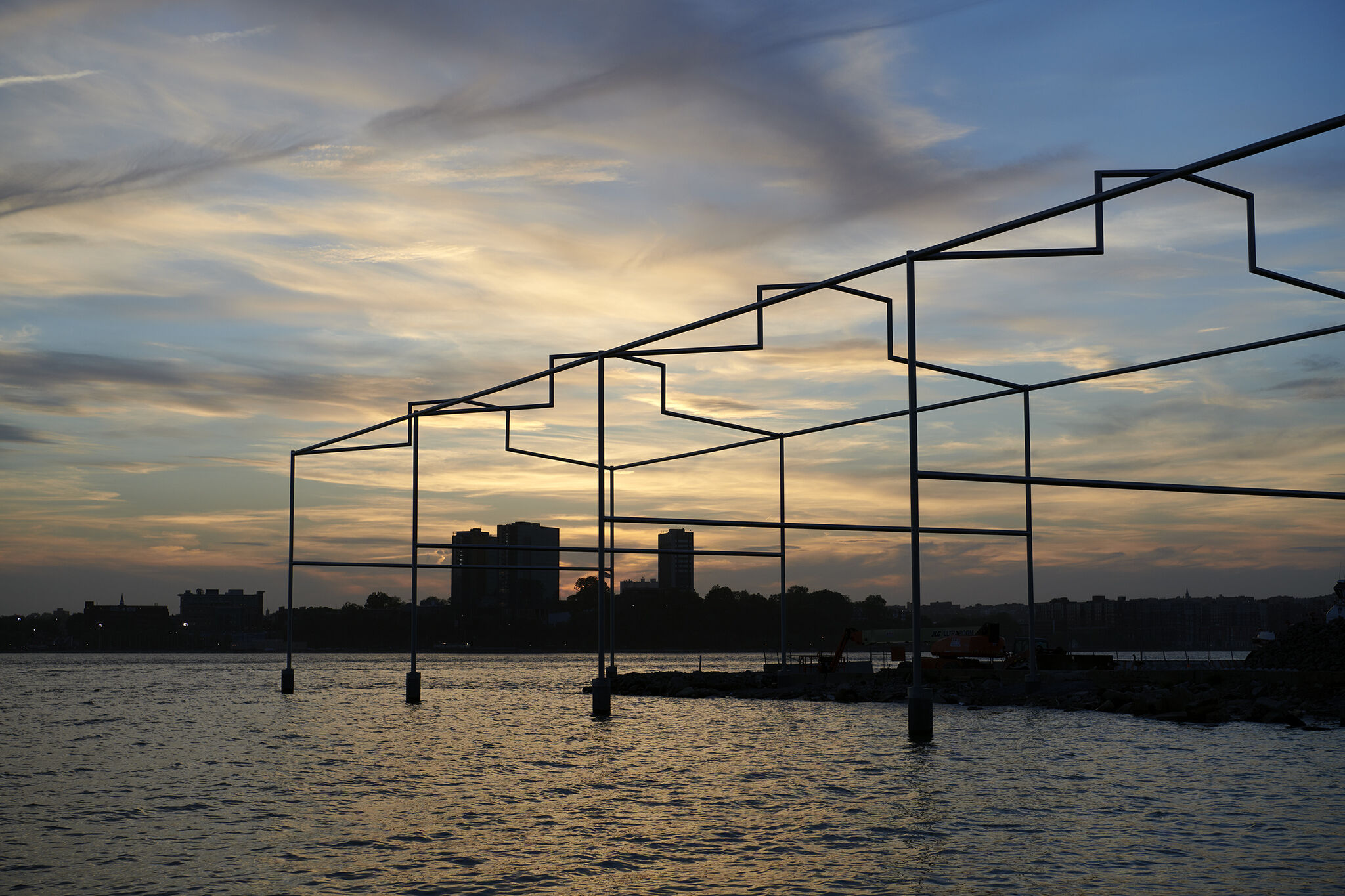 Day's End steel sculpture on the Hudson River, with sunset and New Jersey skyline in the background.