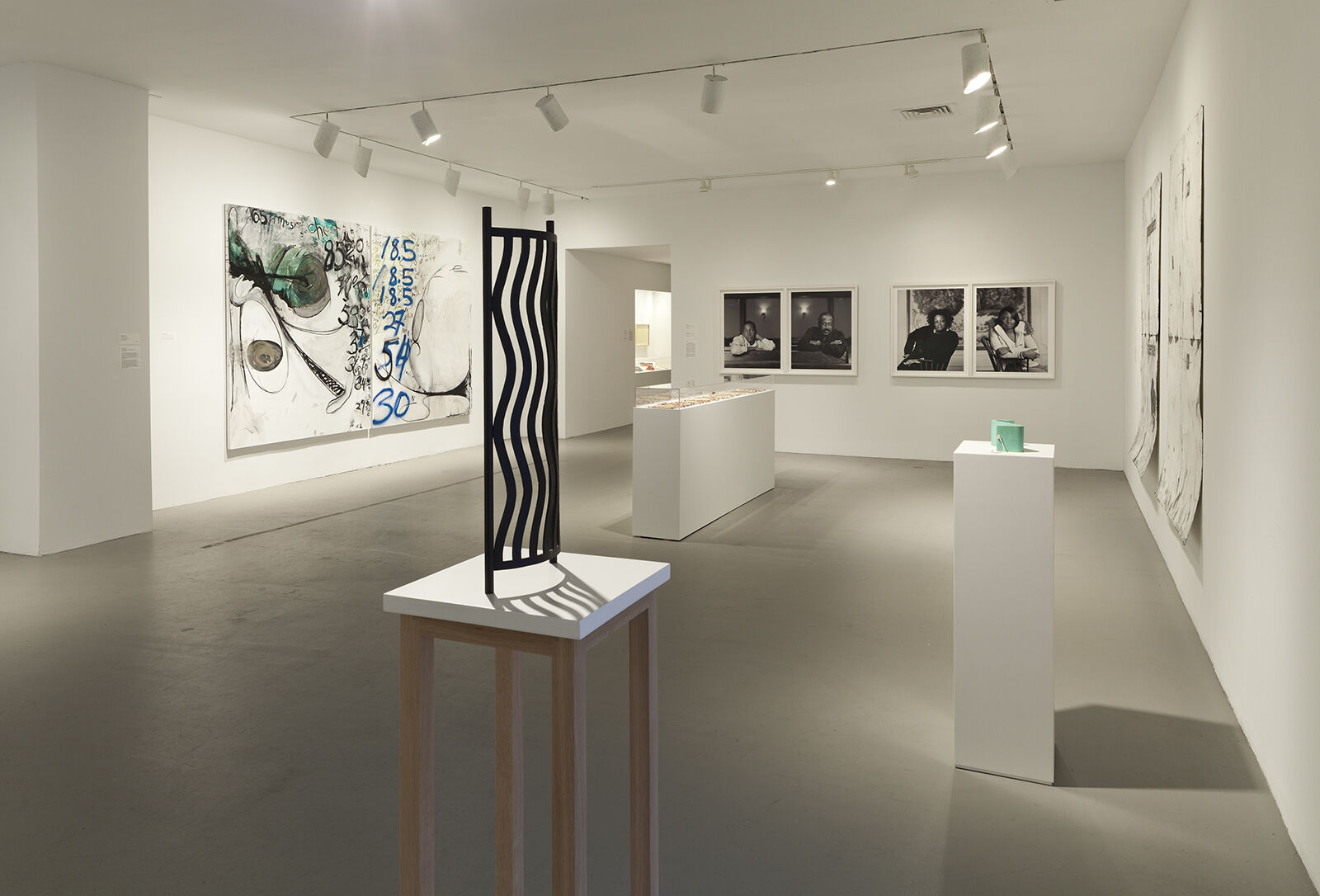 An exhibition gallery with a sculpture on display and works of art on the walls.