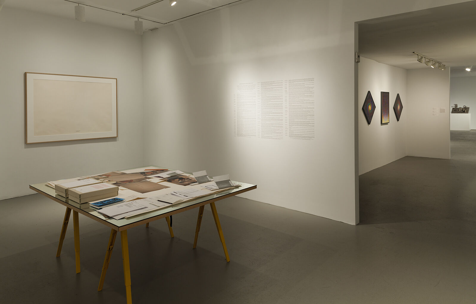 A gallery filled with works of art on the walls and on a table.