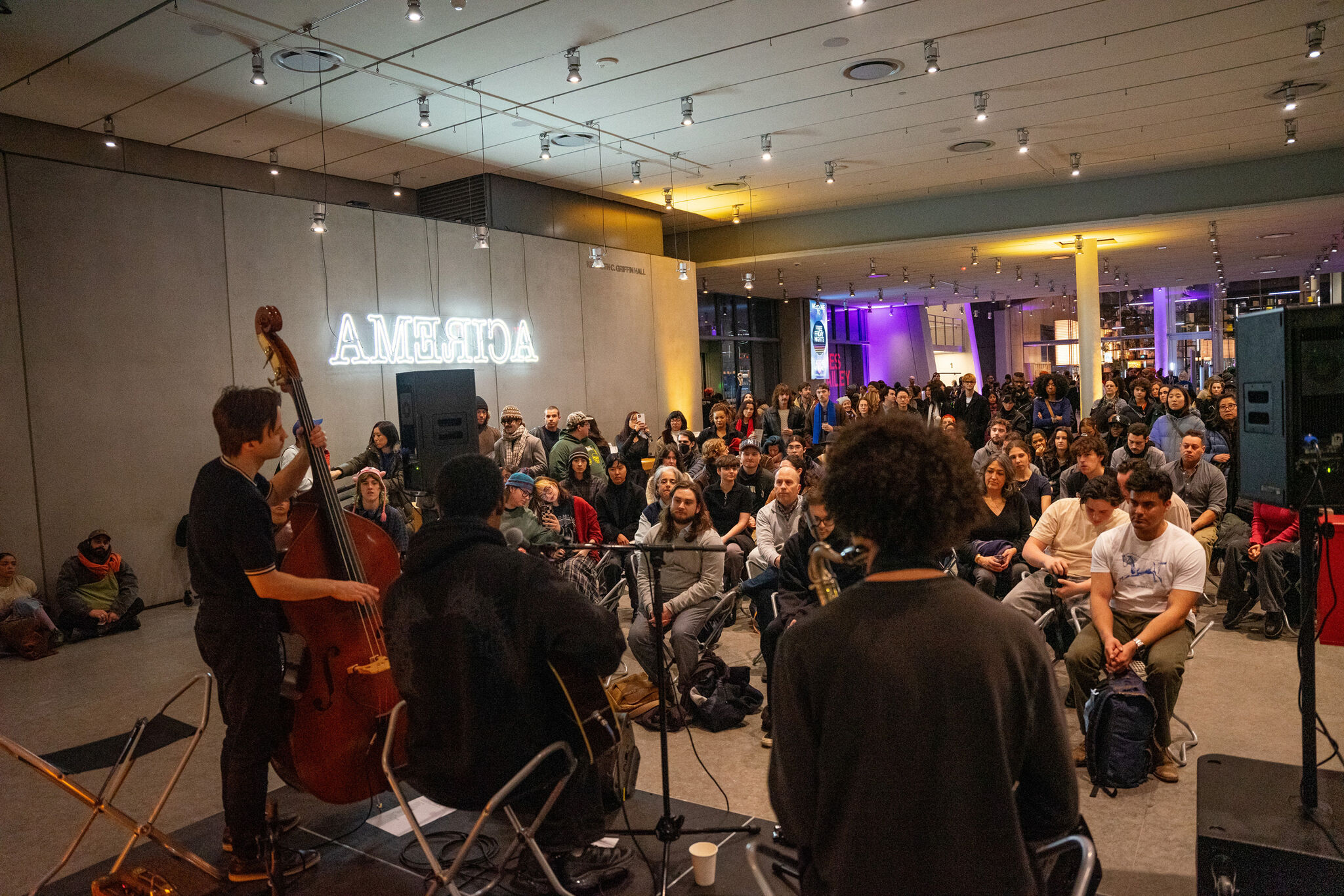 John Roseboro and band perform in front of a full seated and standing audience in the Museum lobby. 