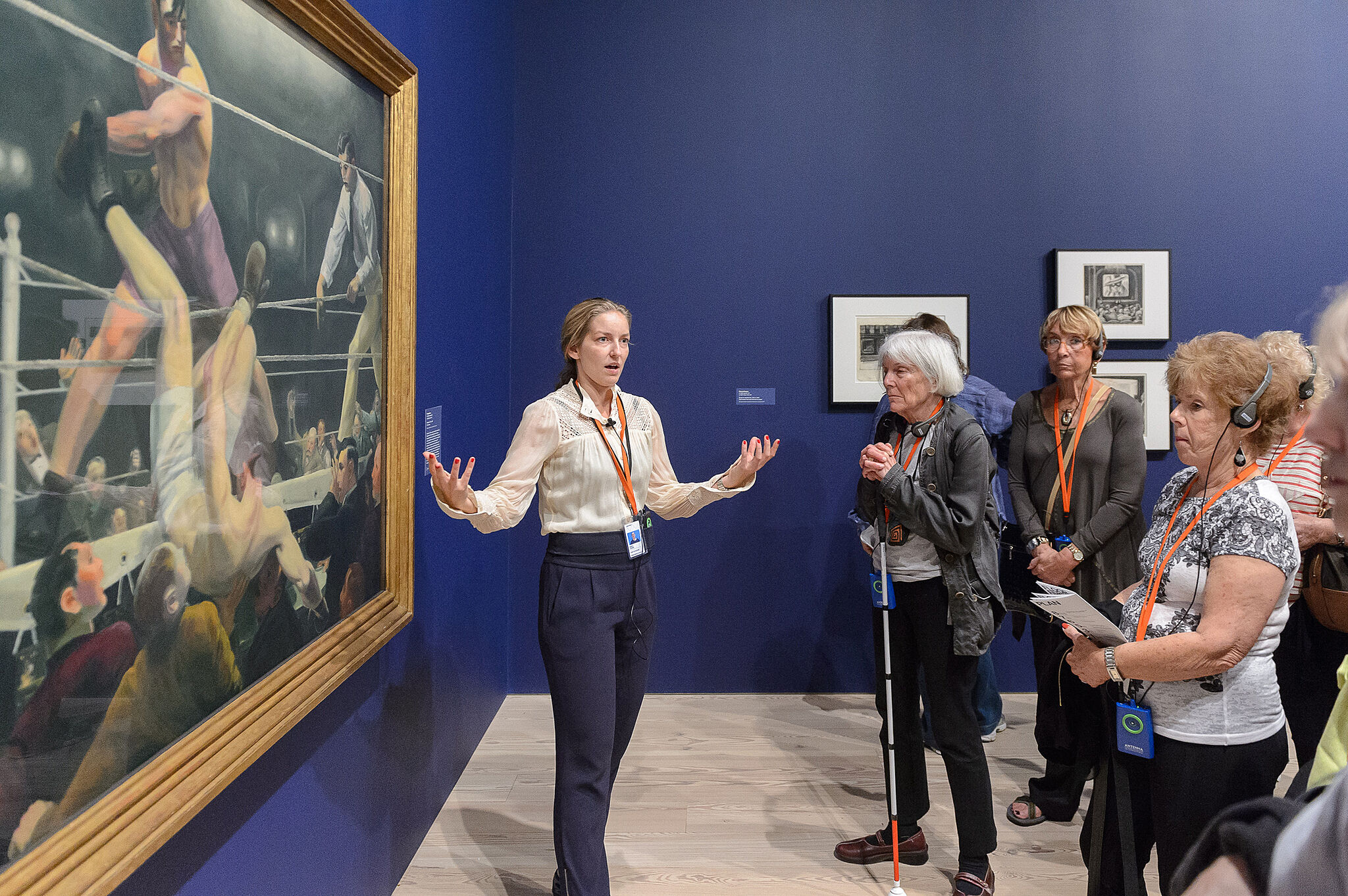A woman stands in front of an artwork with a group of people.