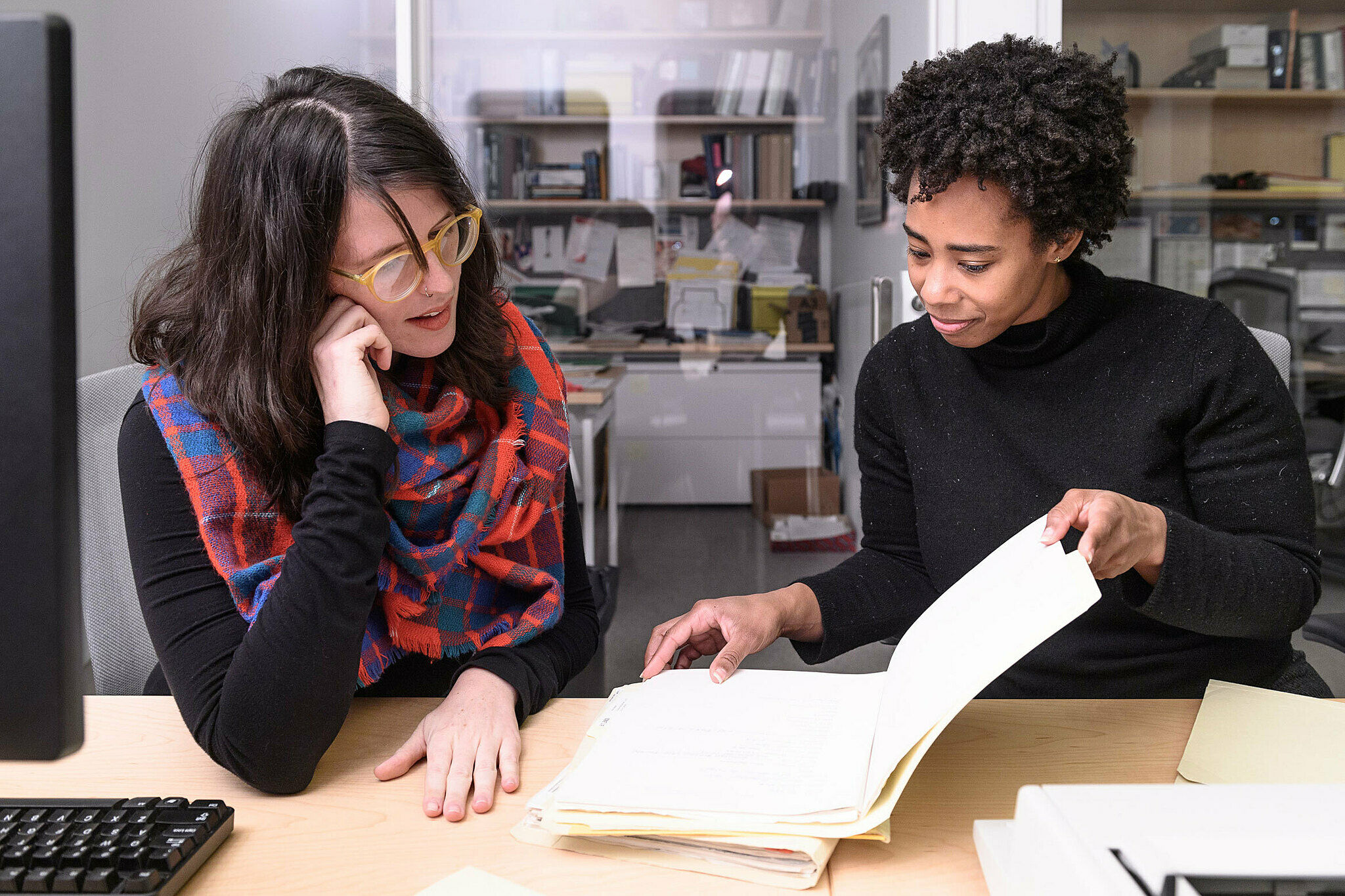 Two artists perusing a book in the archives.