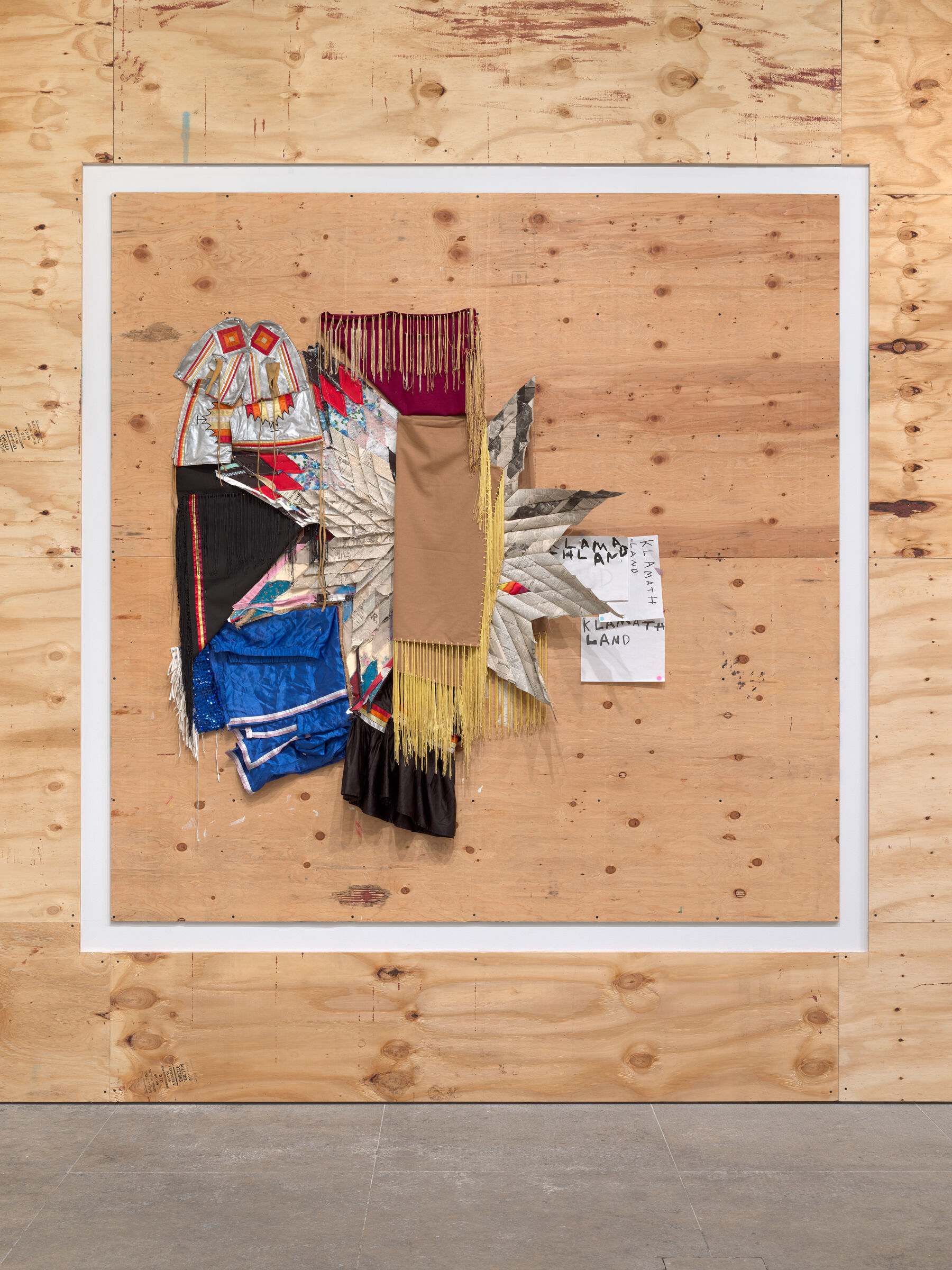 A collage of different materials like fabrics and star quilts and sequins on a light wood wall.