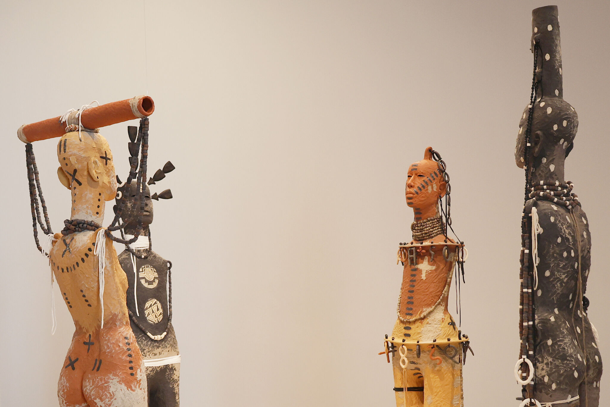 Four sculptures in human form with patterns and jewelry adorning them. 
