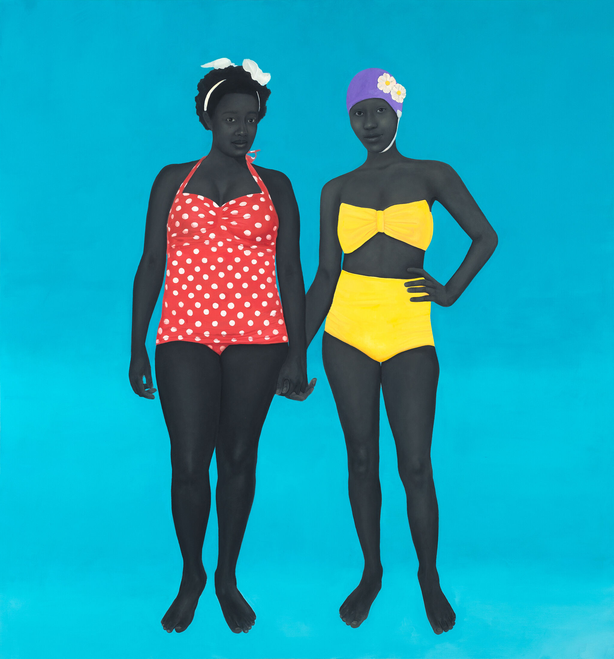 Two women in vintage swimsuits, one in red polka dots, the other in yellow, stand against a bright blue background, holding hands.