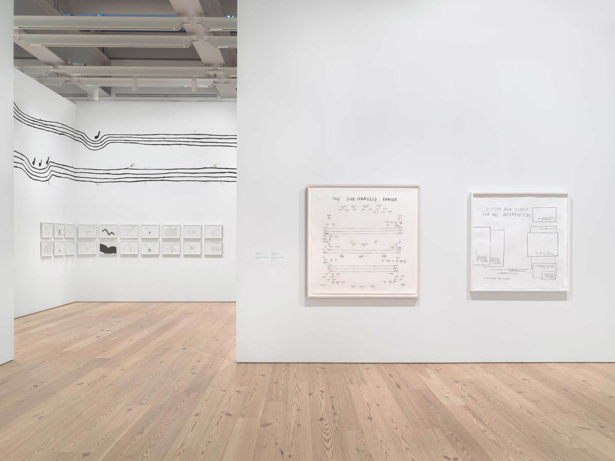 Art gallery with framed sketches and diagrams on white walls, featuring abstract lines and musical notes.