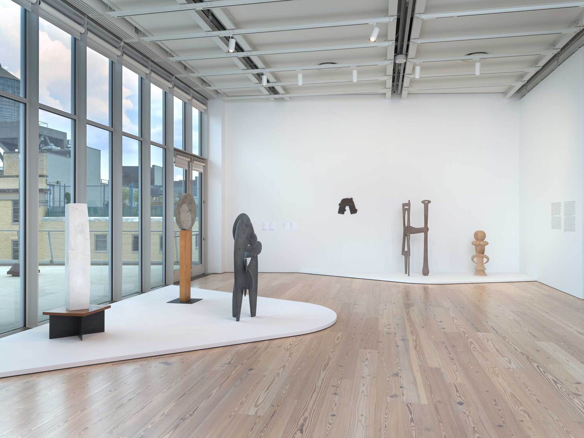 Several abstract sculptures made of stone, wood, and metal are displayed in a bright, modern gallery space.