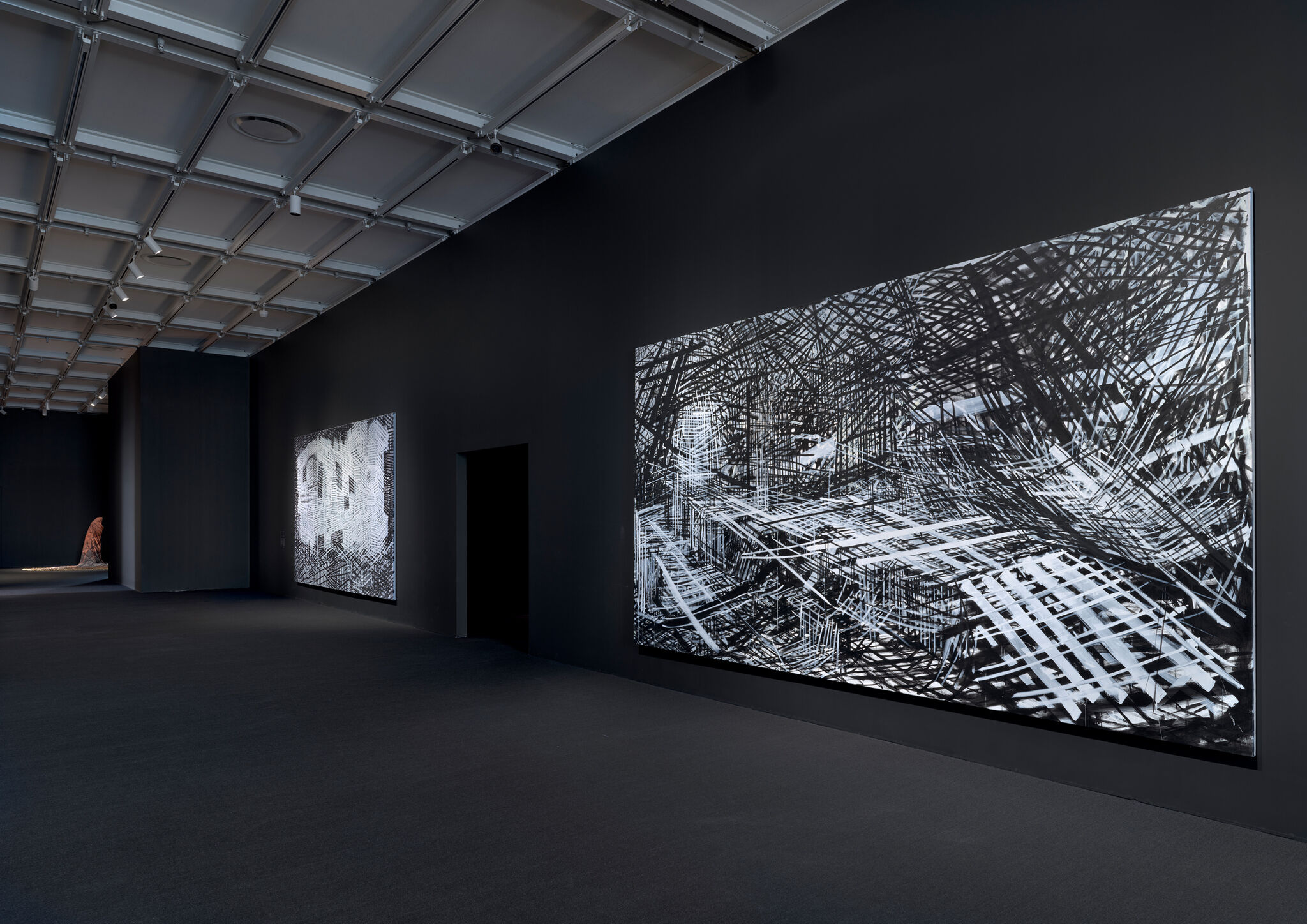 Two large black and white canvases in a dark gallery.