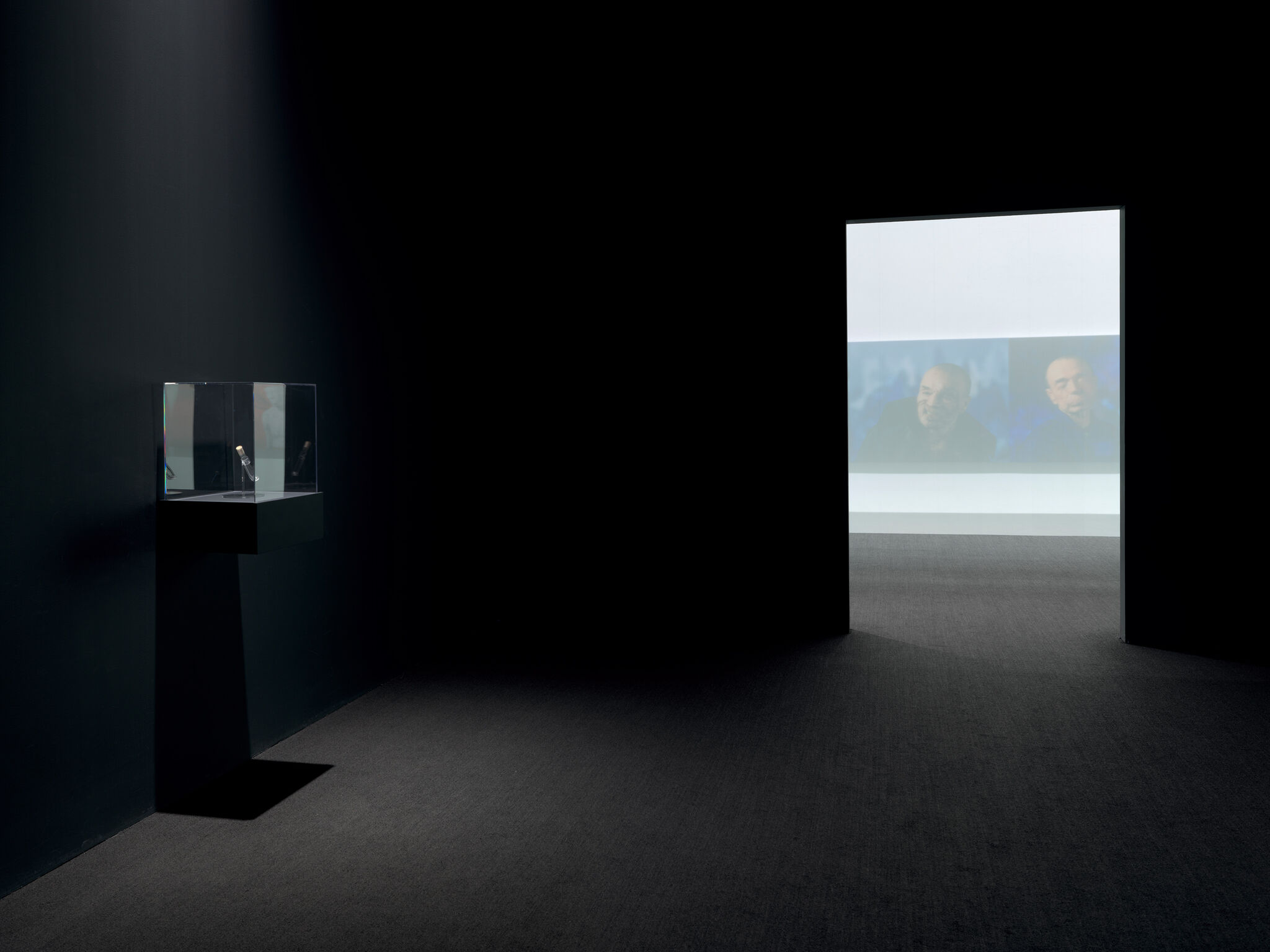 Multiple artworks in a dark gallery.