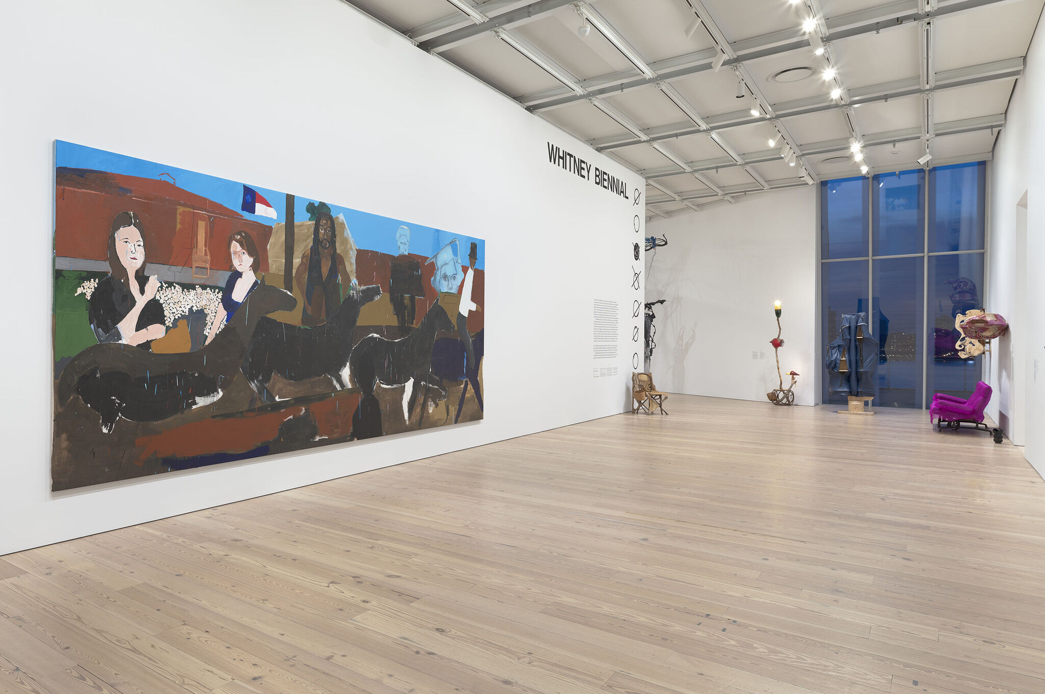 A large painting next to the Whitney Biennial wall text.